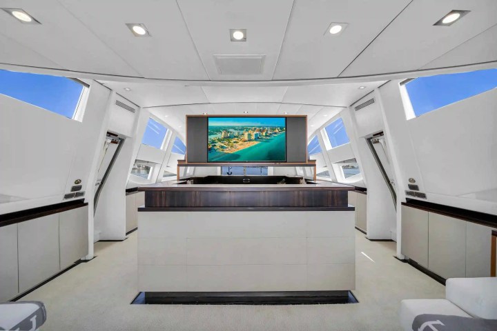 Modern yacht interior with large TV displaying a cityscape, white walls, and sleek design elements.