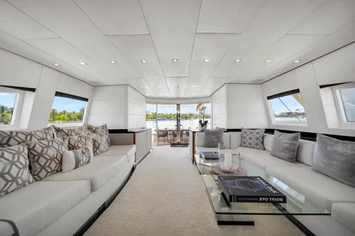 Luxurious yacht interior with white sofas, geometric cushions, and a glass coffee table.