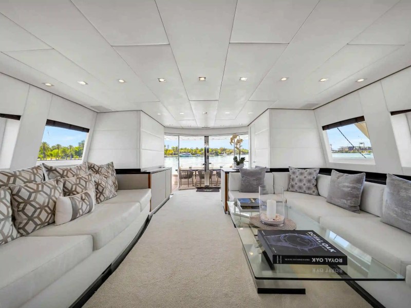 Luxurious yacht interior with white sofas, geometric cushions, and a glass coffee table.