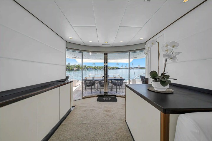 Interior of a yacht with a view of the deck and sea through glass doors, featuring a potted orchid on a counter.