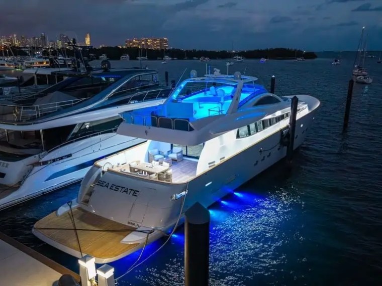 Luxury yacht docked at night with blue lights in a marina.