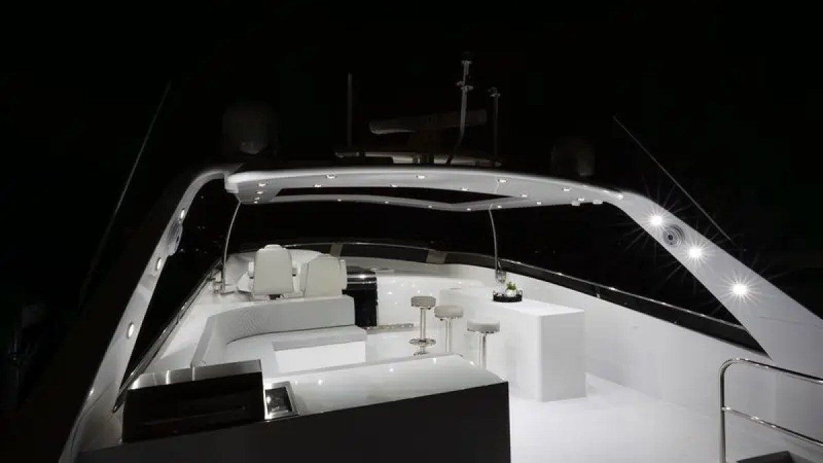 Luxurious yacht deck at night with bar stools and seating under illuminated canopy.