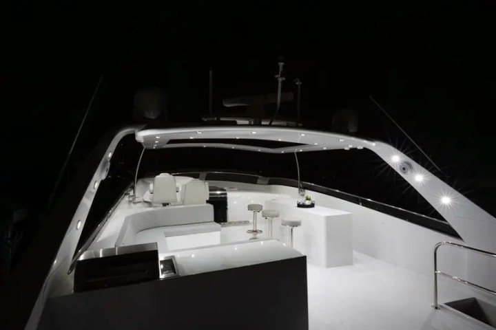 Luxurious yacht deck at night with bar stools and seating under illuminated canopy.