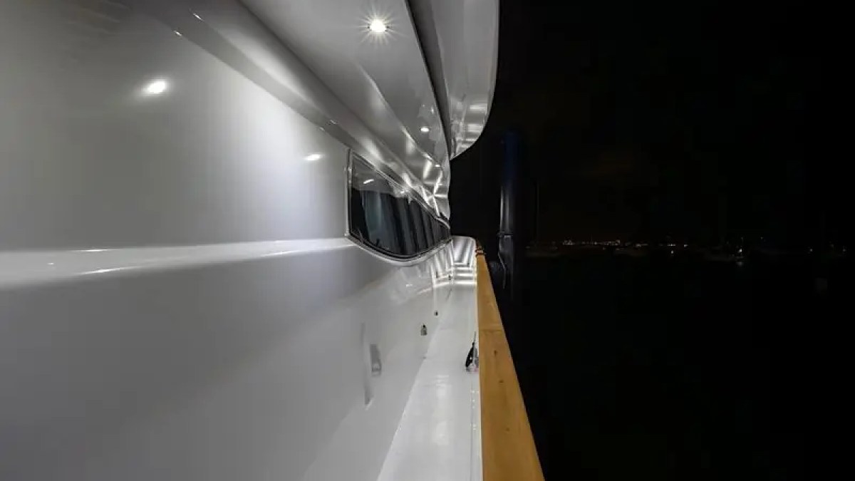 Close-up of a yacht's exterior at night with bright lights along the side.