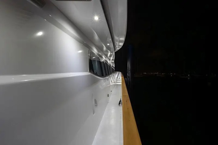 Close-up of a yacht's exterior at night with bright lights along the side.