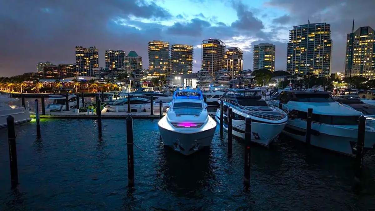 Boats docked at a marina with city skyline in the background at dusk.