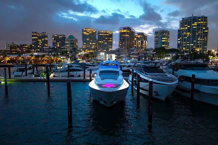 Boats docked at a marina with city skyline in the background at dusk.
