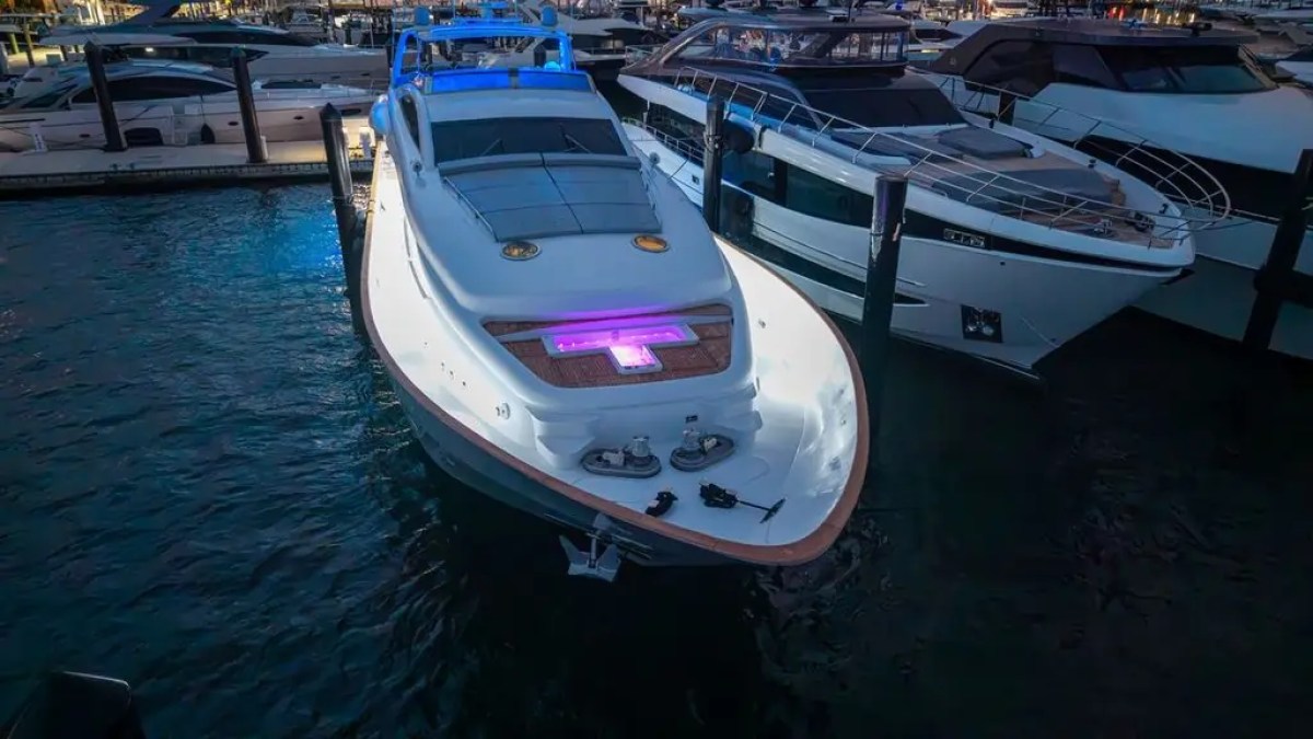 Luxury yachts docked at night with colorful lights illuminating the water.