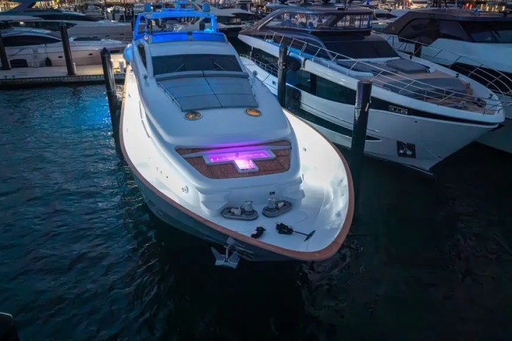 Luxury yachts docked at night with colorful lights illuminating the water.