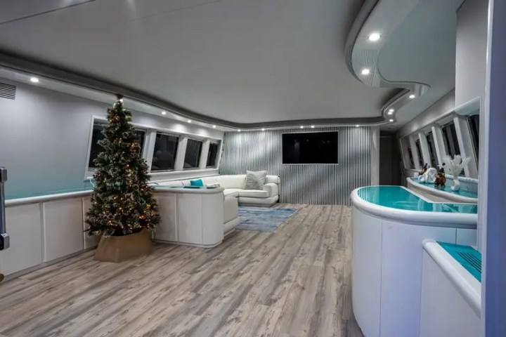 Modern interior with a Christmas tree, white sofa, and blue accents in a spacious room with wood flooring.
