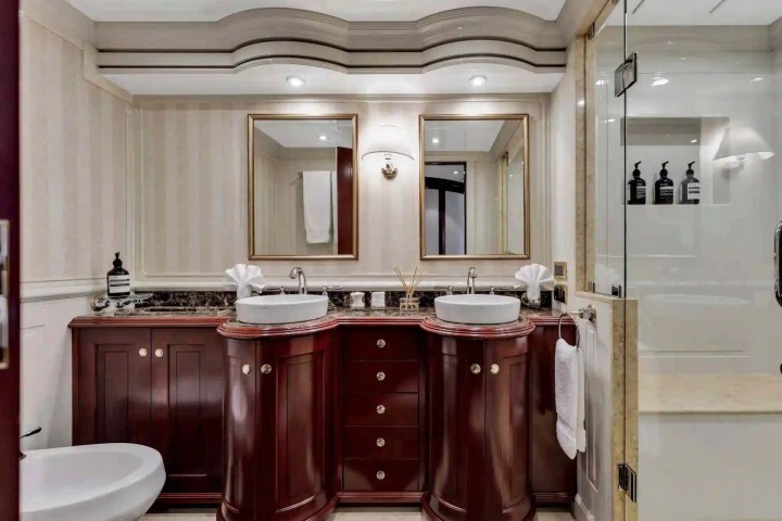 Elegant bathroom with double sinks, mirrors, and a glass shower on the right.