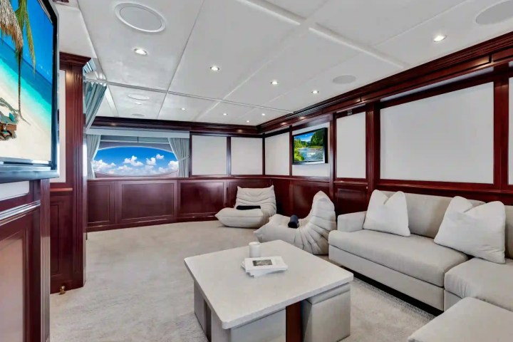 Luxurious yacht interior with sofas, a table, and ocean-view windows.