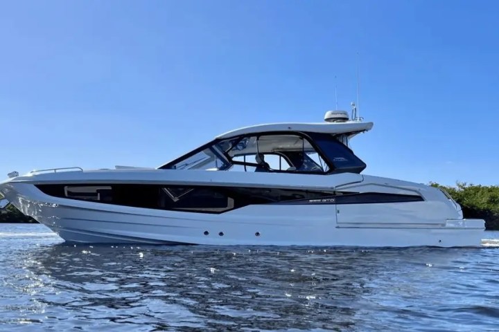White motorboat on calm water under a clear blue sky.