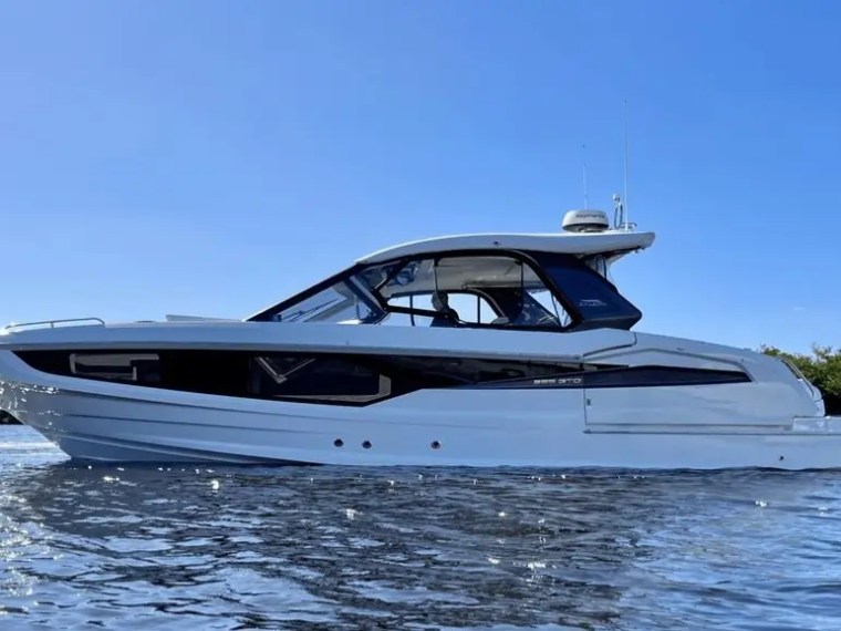 White motorboat on calm water under a clear blue sky.