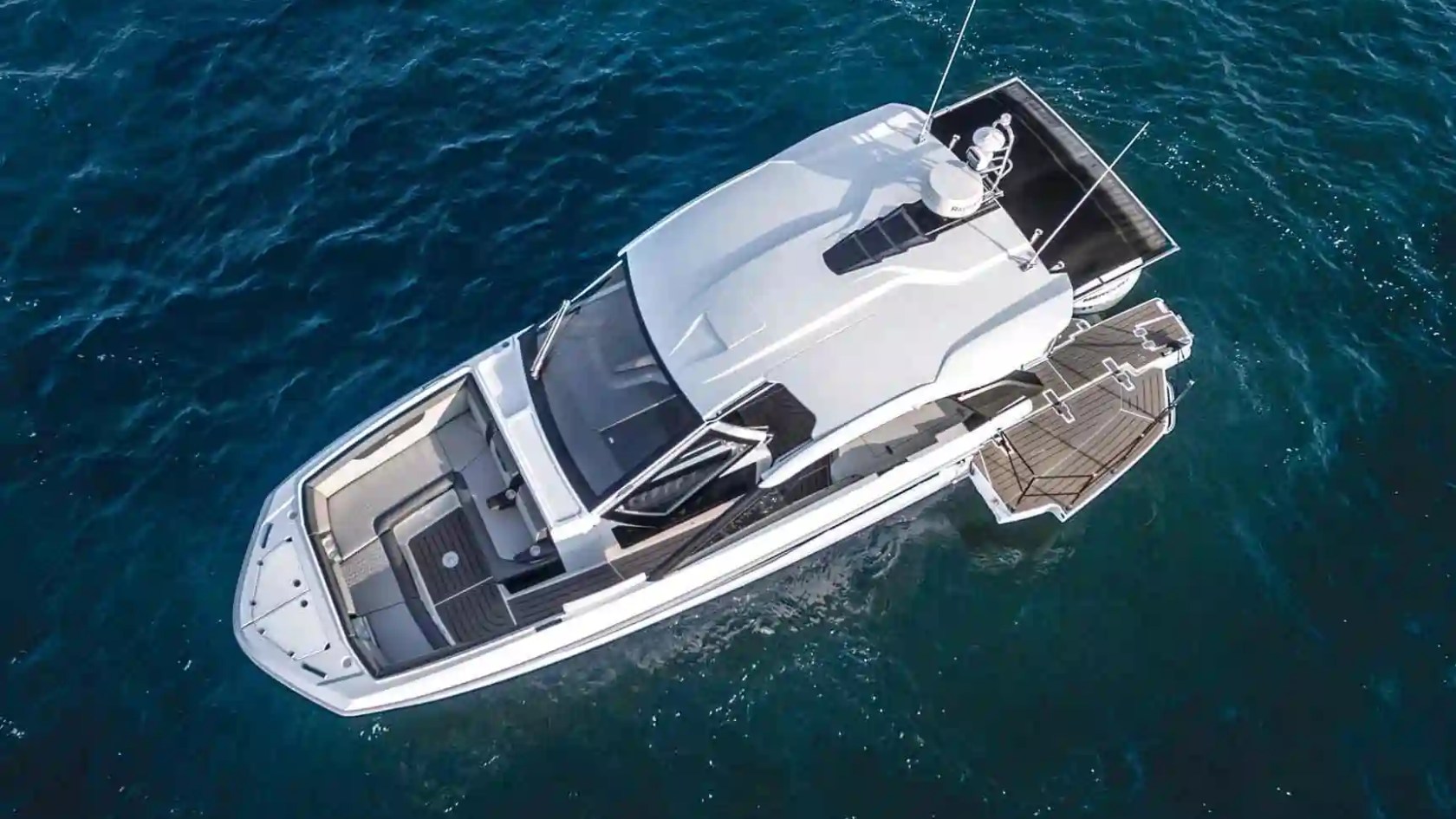 Aerial view of a white luxury yacht on blue ocean water.