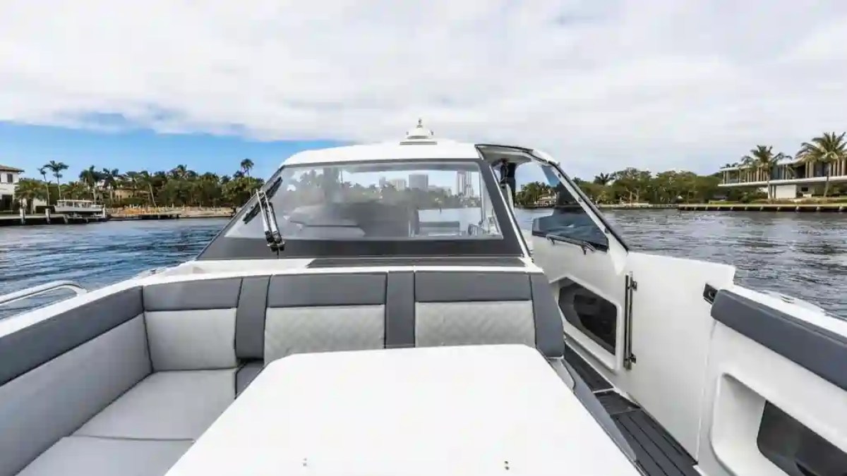 View from yacht deck with seating area, overlooking calm water and palm trees in the background.
