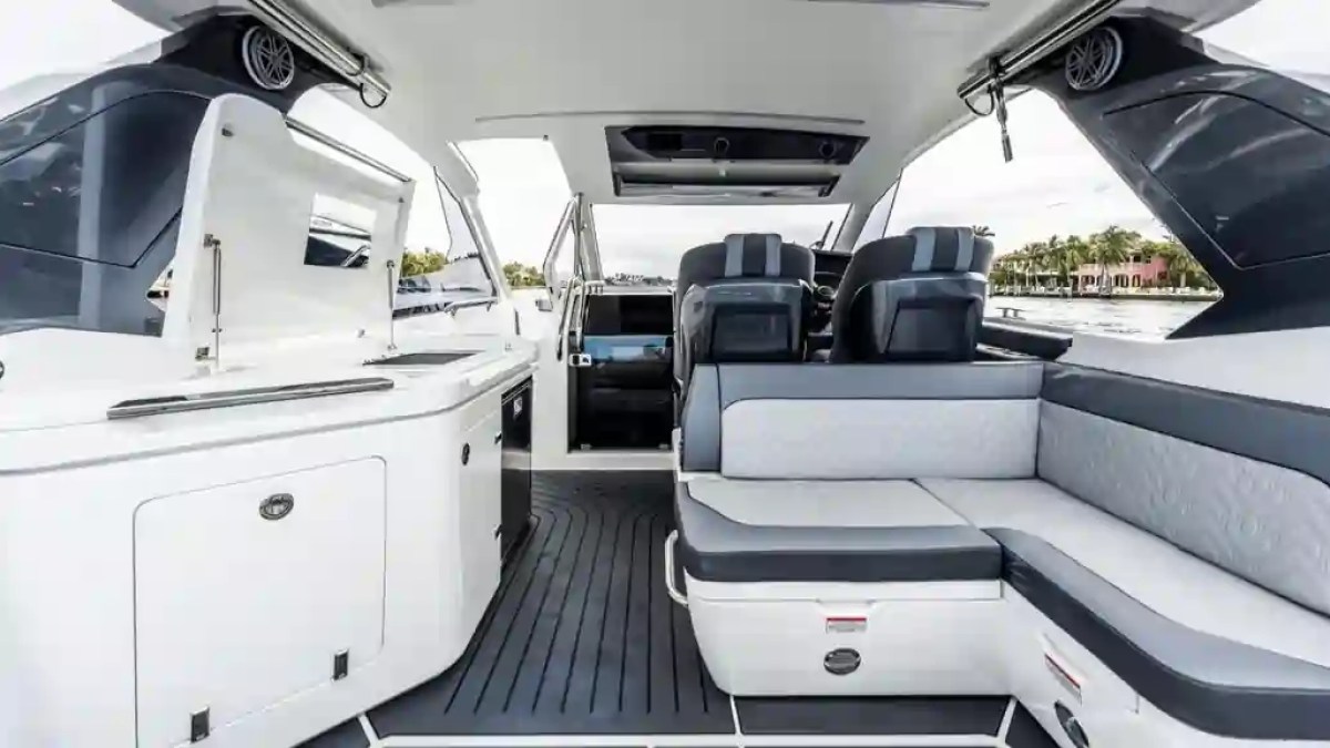 Interior of a modern boat with seats, open-air design, and a small kitchenette.