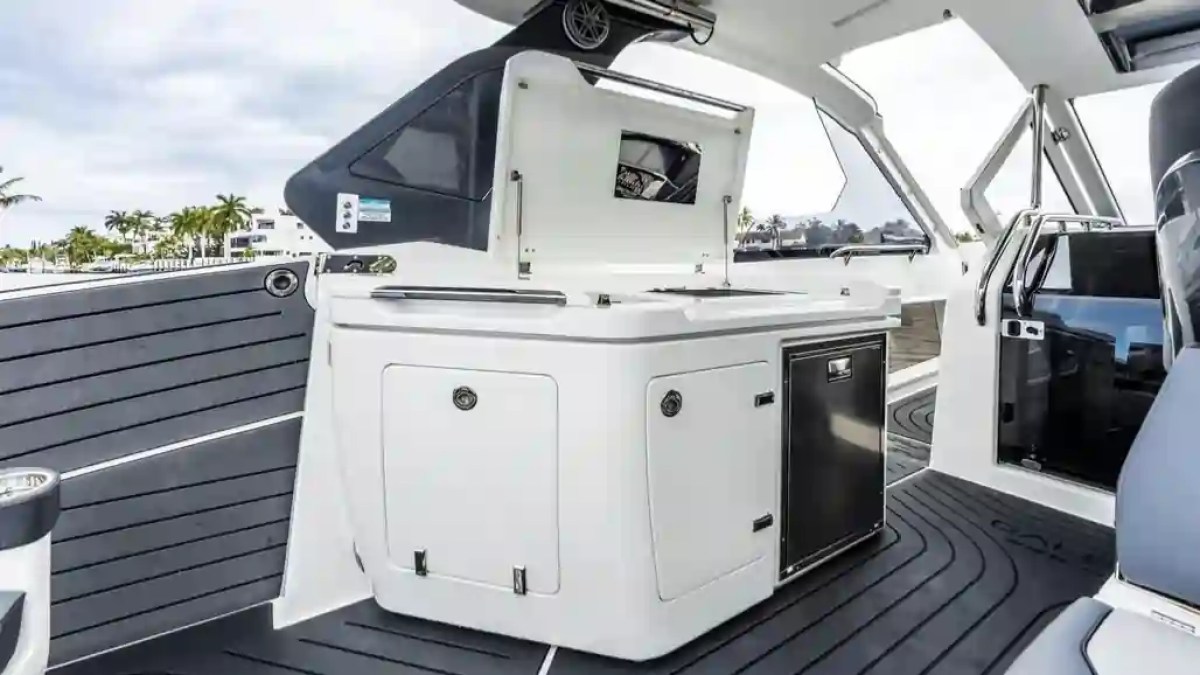 Luxury yacht interior with kitchenette, dark flooring, and stainless steel appliances.