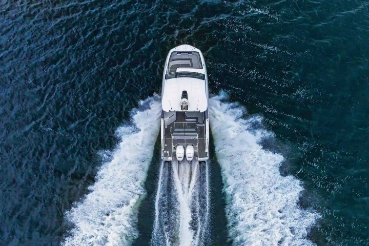 Overhead view of a white yacht speeding through blue water, leaving a wake behind.