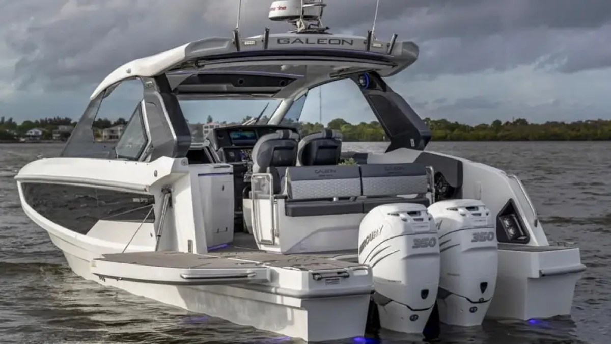 Luxury boat with dual engines and seating, cruising on a cloudy day.