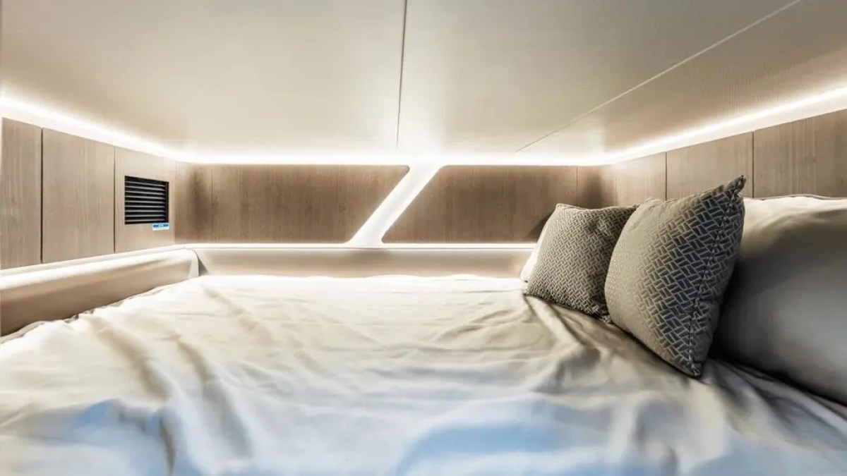 Modern bed with ambient lighting and two decorative pillows in a sleek, minimalist setting.
