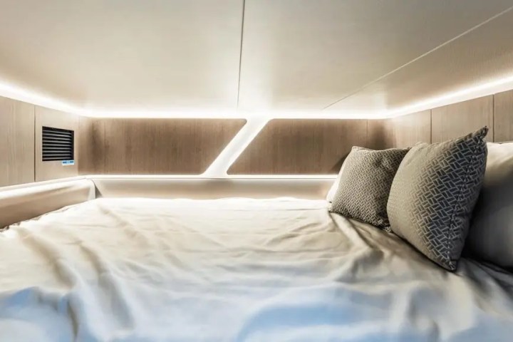 Modern bed with ambient lighting and two decorative pillows in a sleek, minimalist setting.