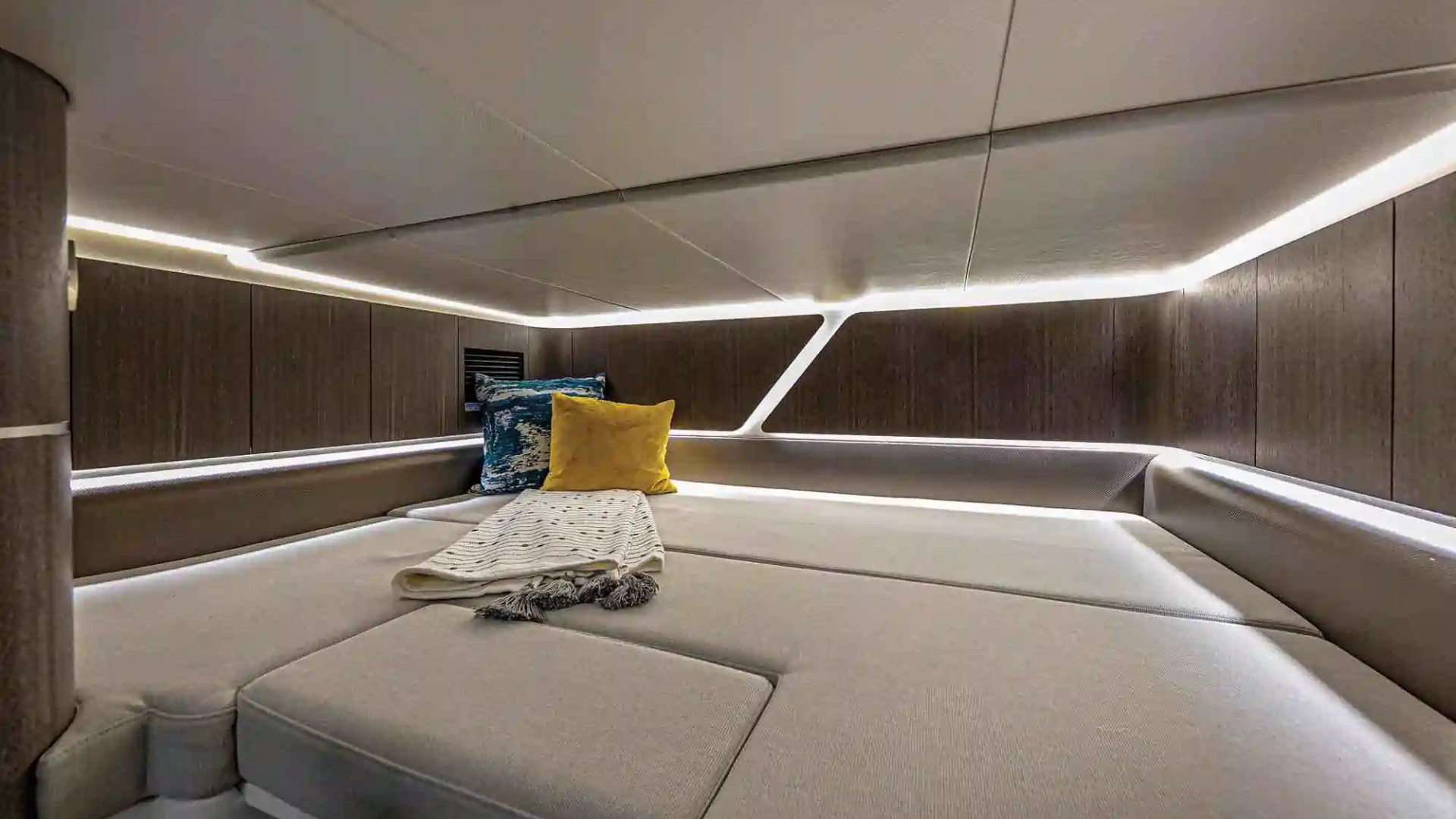 Boat cabin with gray seating, accent pillows, and soft lighting.