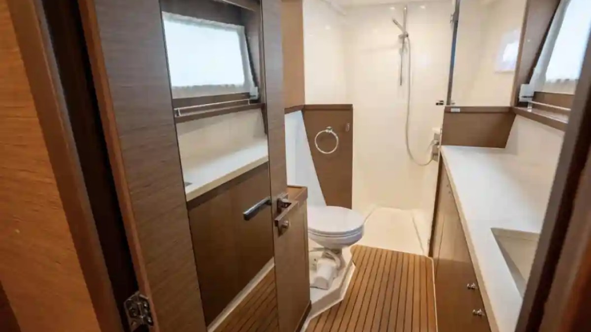 Modern bathroom with wood accents, shower, toilet, and sink on a boat.