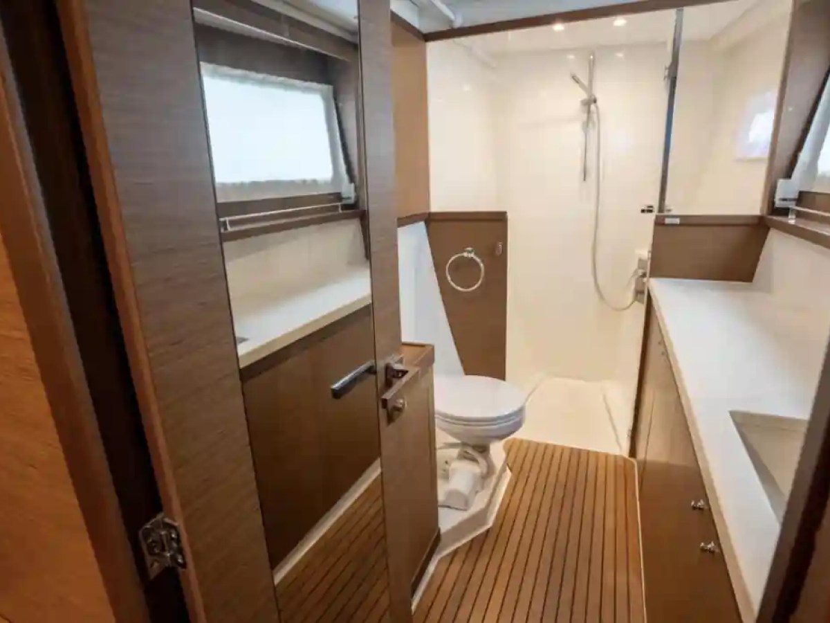 Modern bathroom with wood accents, shower, toilet, and sink on a boat.