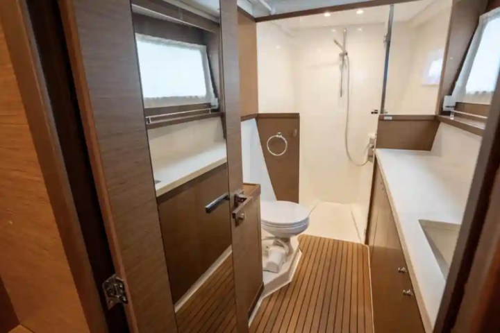 Modern bathroom with wood accents, shower, toilet, and sink on a boat.