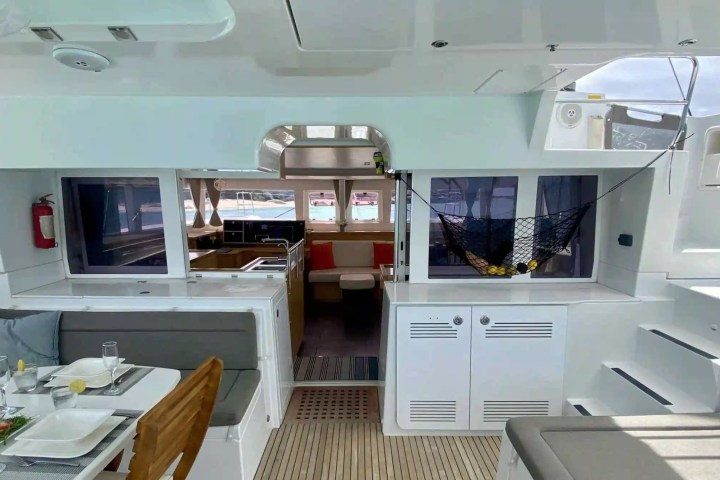 Interior of a yacht with dining area, kitchen, and net holding fruits.