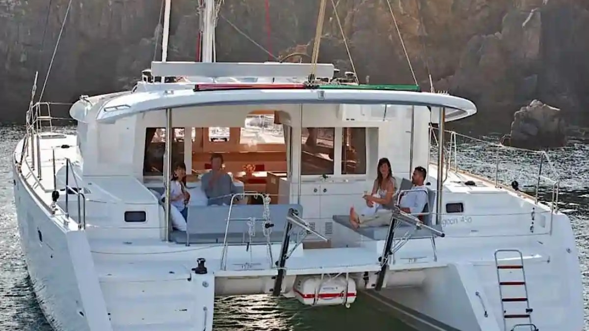 People relaxing on a catamaran in a scenic coastal area.