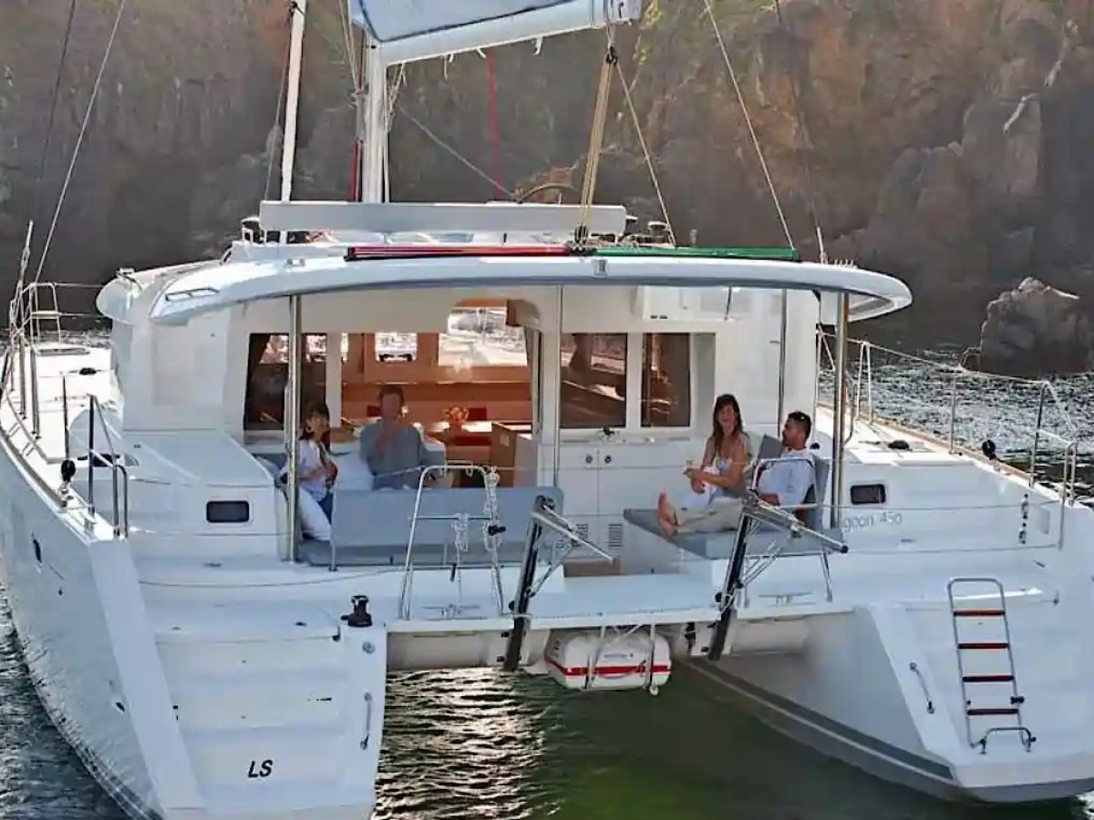 People relaxing on a catamaran in a scenic coastal area.
