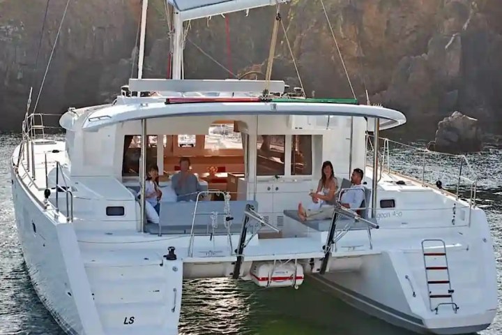 People relaxing on a catamaran in a scenic coastal area.