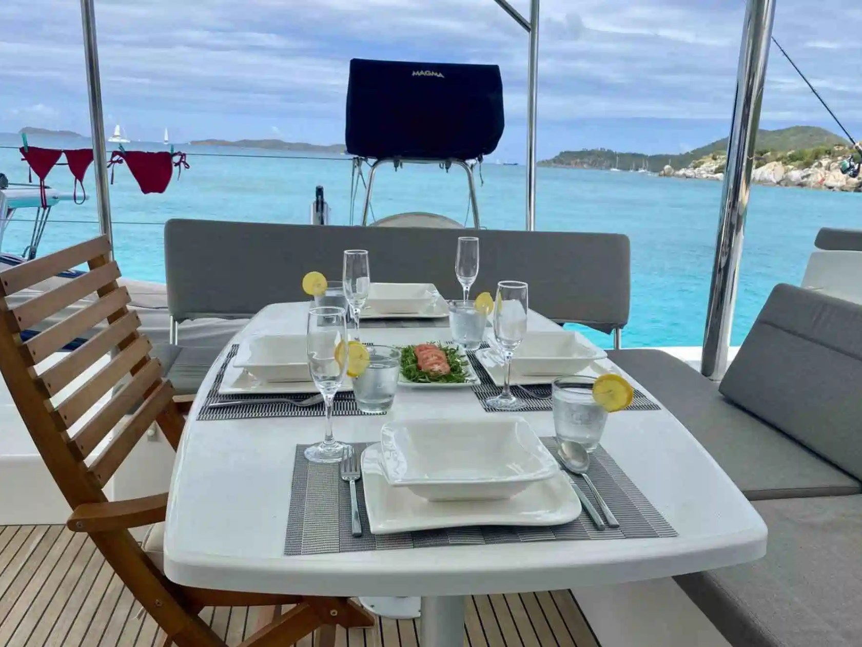 Dining table on a boat set for four with sea and island view.