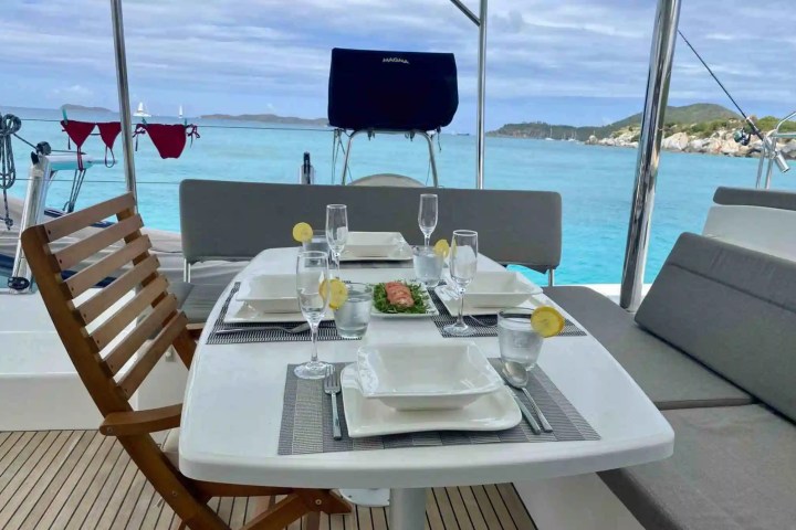 Dining table on a boat set for four with sea and island view.
