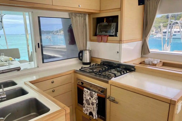 Boat kitchen with a stove, oven, sink, and window view of the sea.