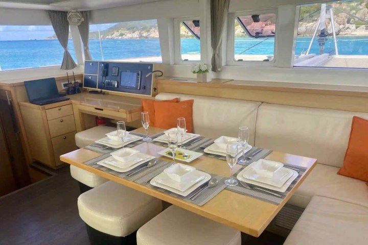 Interior of a yacht with a set dining table and ocean view through windows.