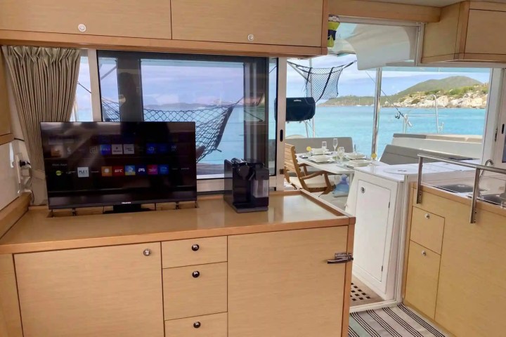 Interior of a boat with a TV, cabinets, and seating area; sea view outside through windows.