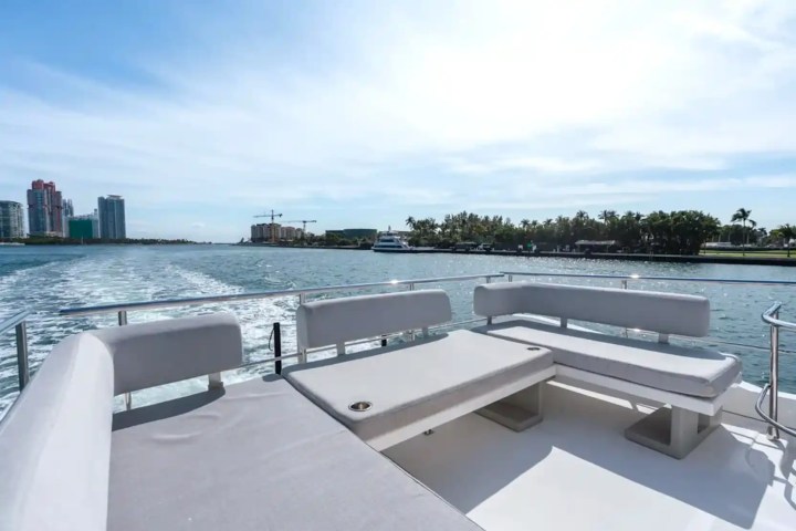 View from a boat with seating, overlooking water and distant city skyline under a clear sky.