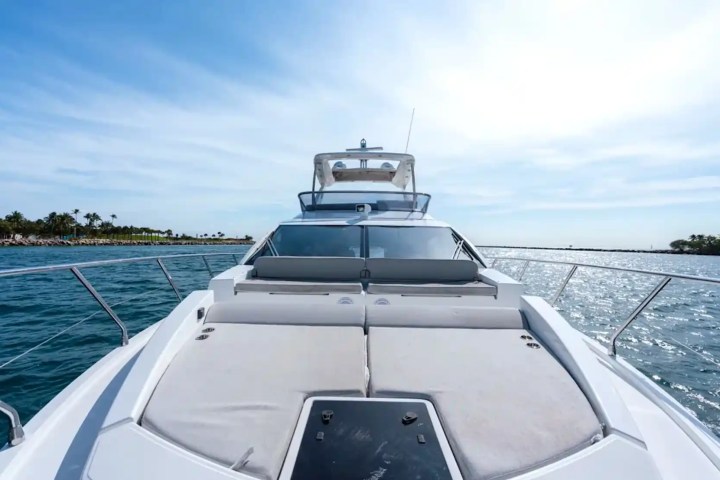 View from a boat deck with blue ocean and distant coastline under a clear sky.