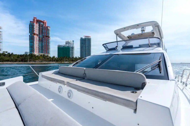 Front deck of a yacht with city skyline and ocean in the background.