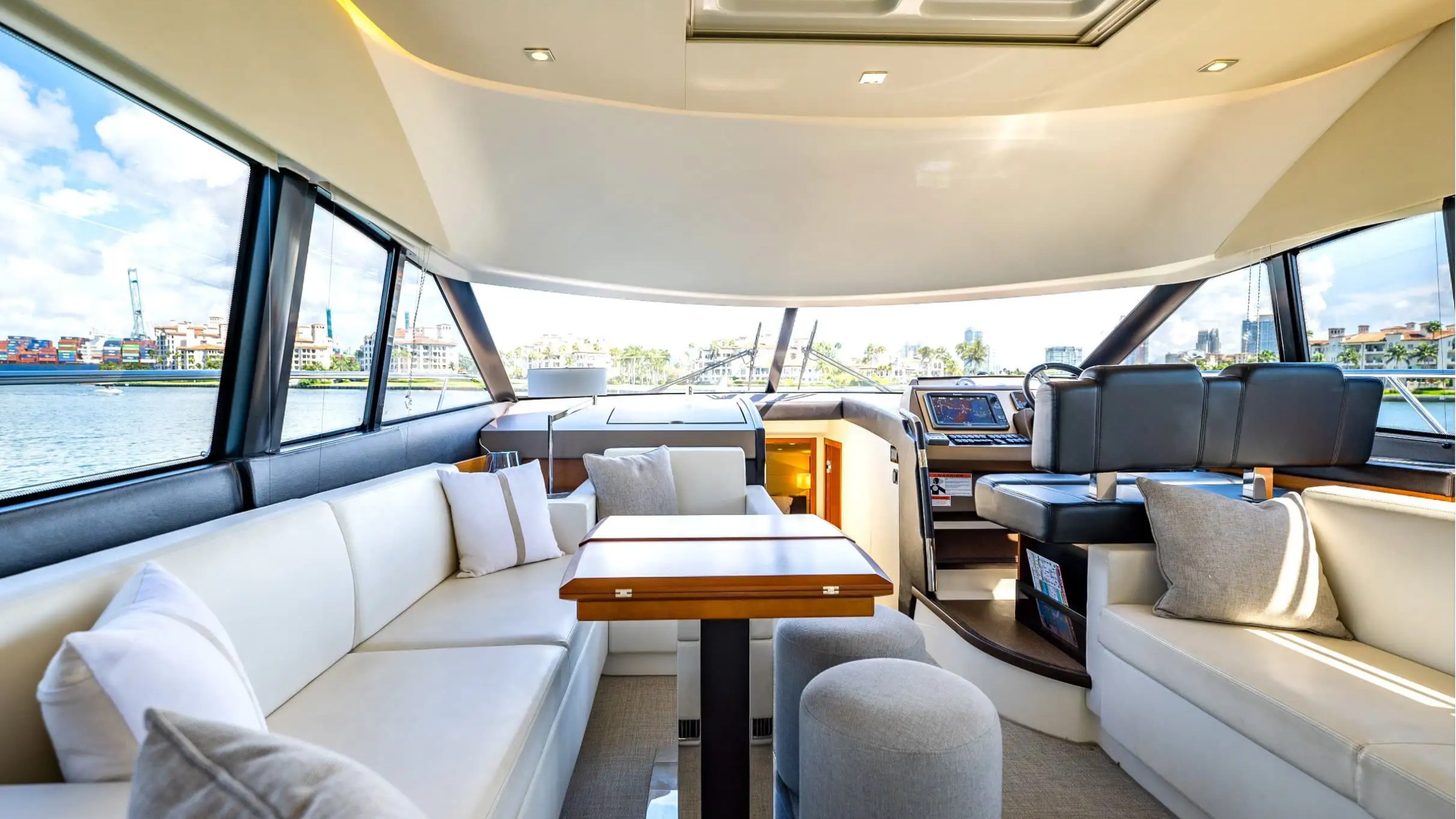 Luxurious yacht interior with spacious seating and large windows showing a harbor view.