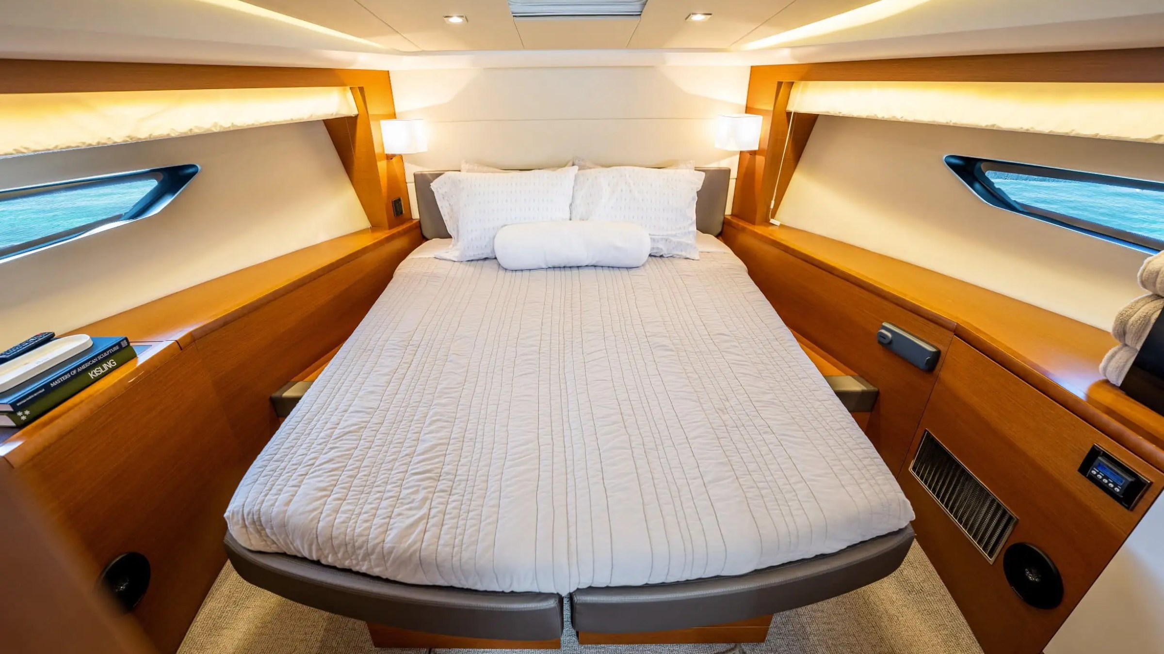 Cozy yacht cabin with a double bed, wood paneling, and small windows on both sides.