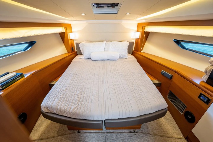 Cozy yacht cabin with a double bed, wood paneling, and small windows on both sides.