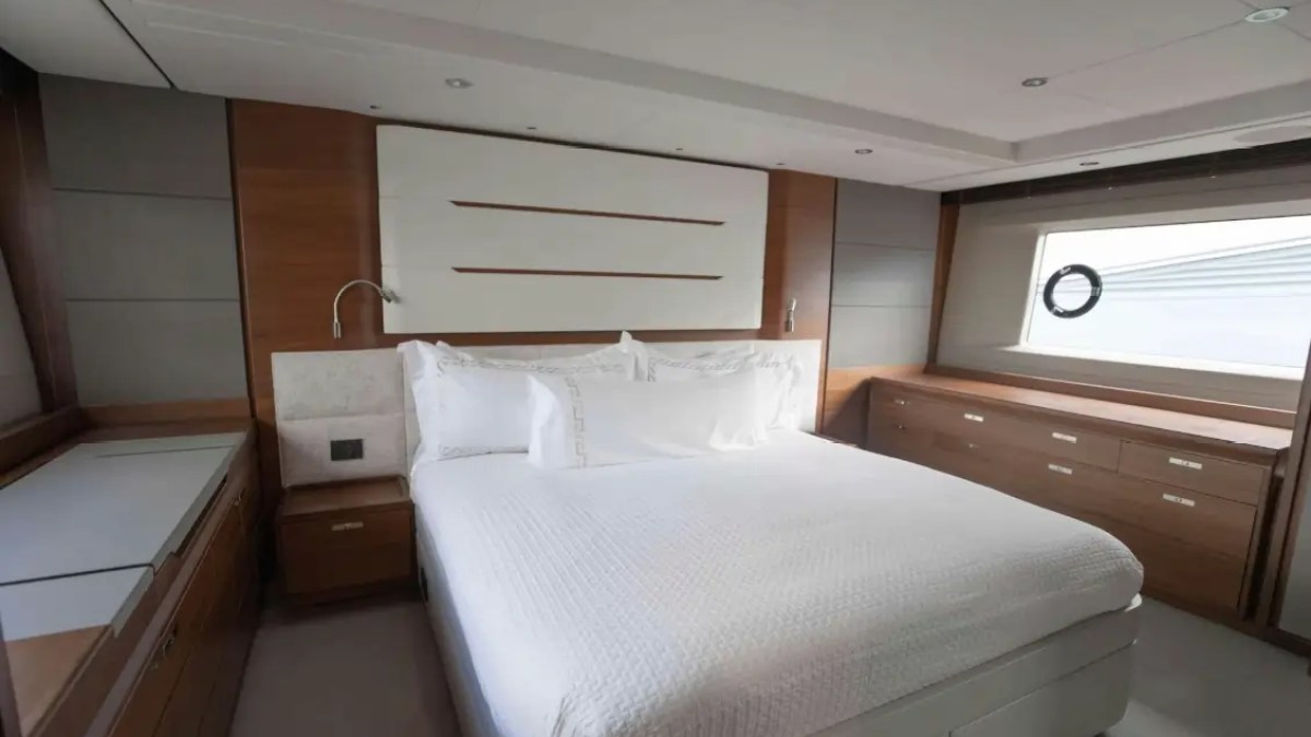 Modern bedroom with a large bed, white linens, wood paneling, and a porthole window.