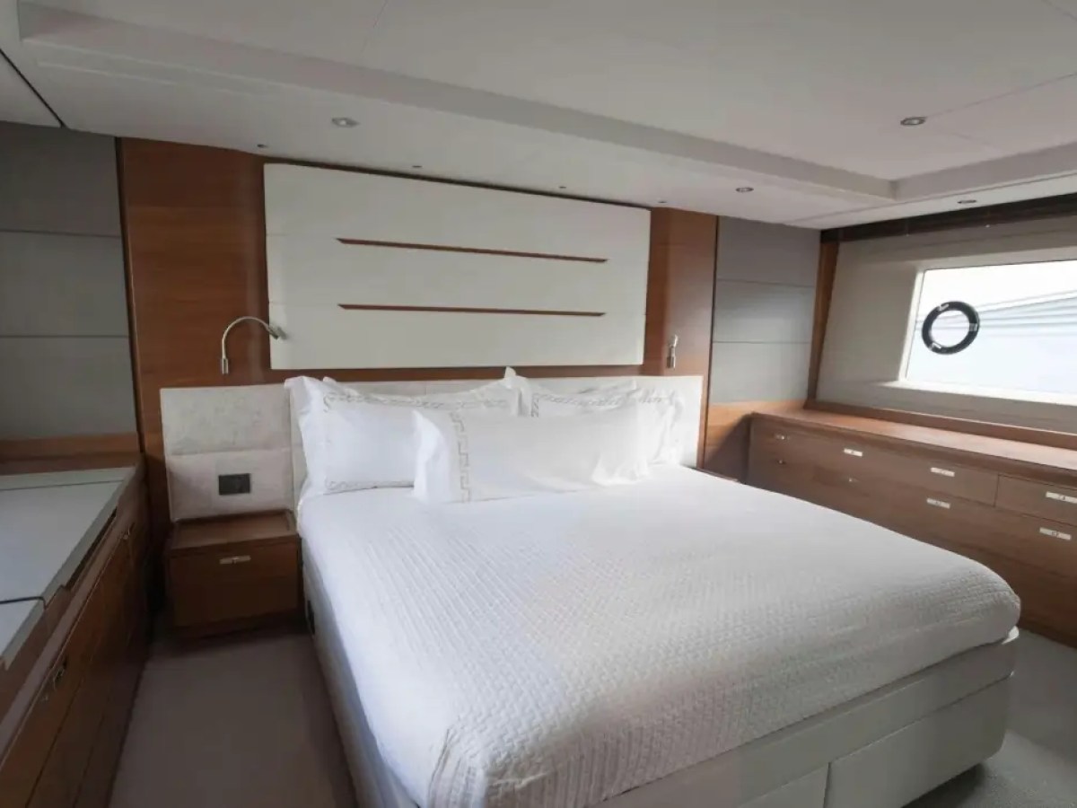 Modern bedroom with a large bed, white linens, wood paneling, and a porthole window.