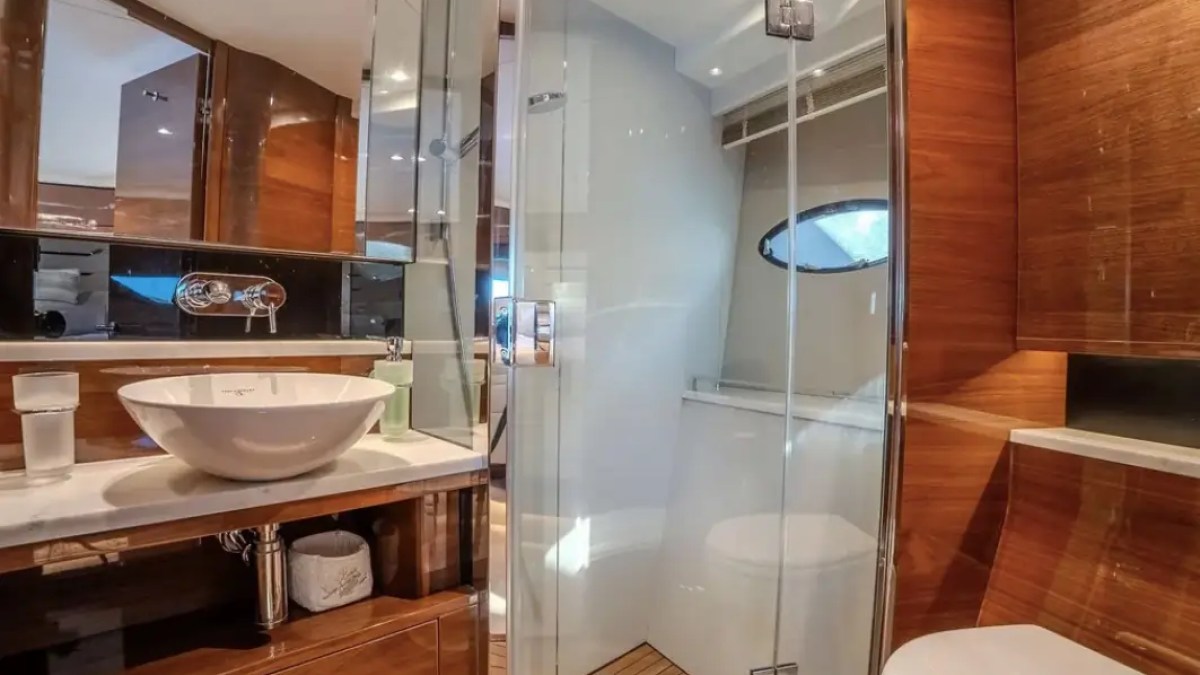 Modern bathroom with a vessel sink, glass shower, and wood accents.