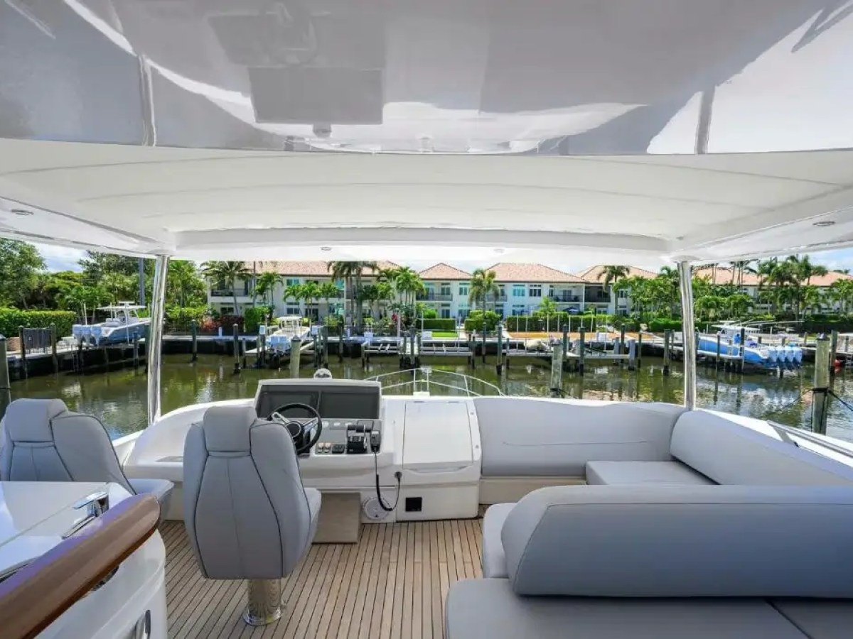 View from inside a boat with gray seating, overlooking a marina and waterfront homes with palm trees.