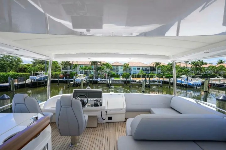 View from inside a boat with gray seating, overlooking a marina and waterfront homes with palm trees.